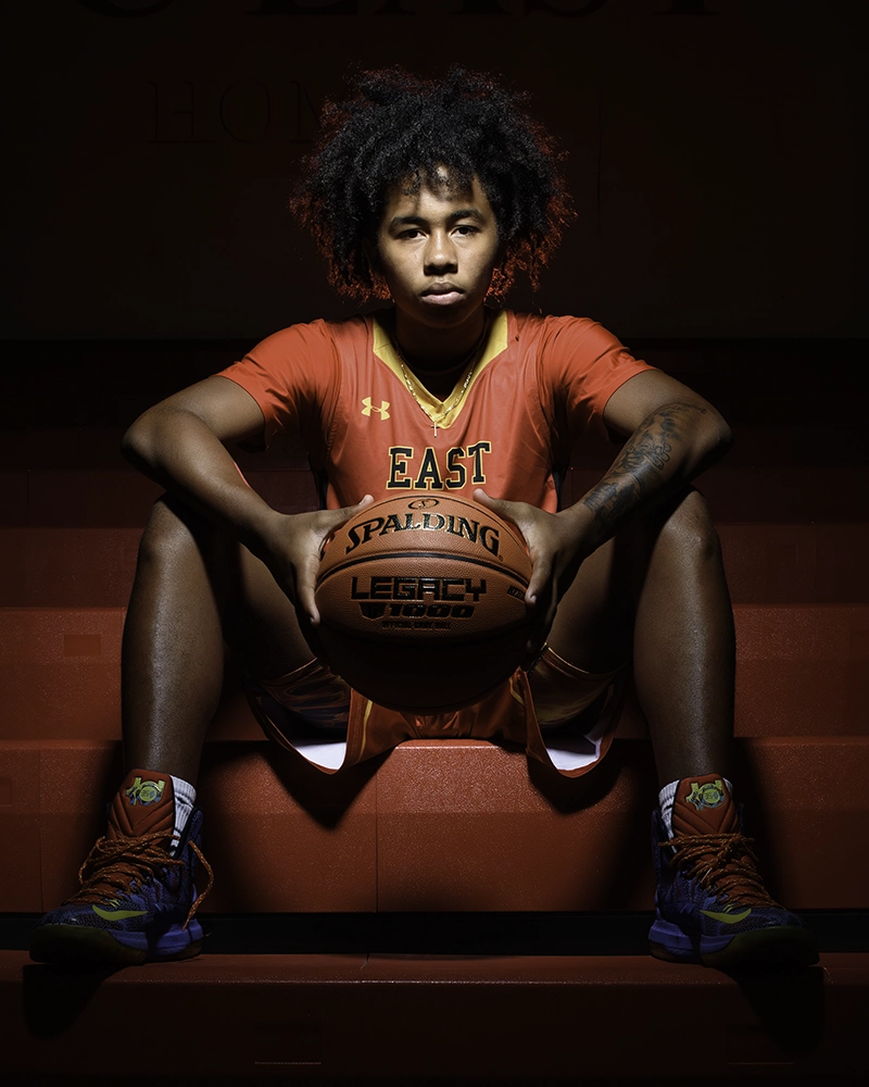 Basketball player sitting on the gym bleachers.