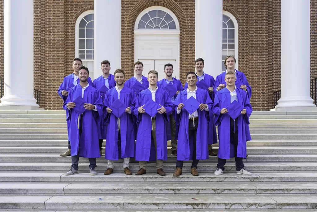 University of Delaware senior photographer - 11 male graduates in their caps and gowns posing on the steps to Memorial Hall.